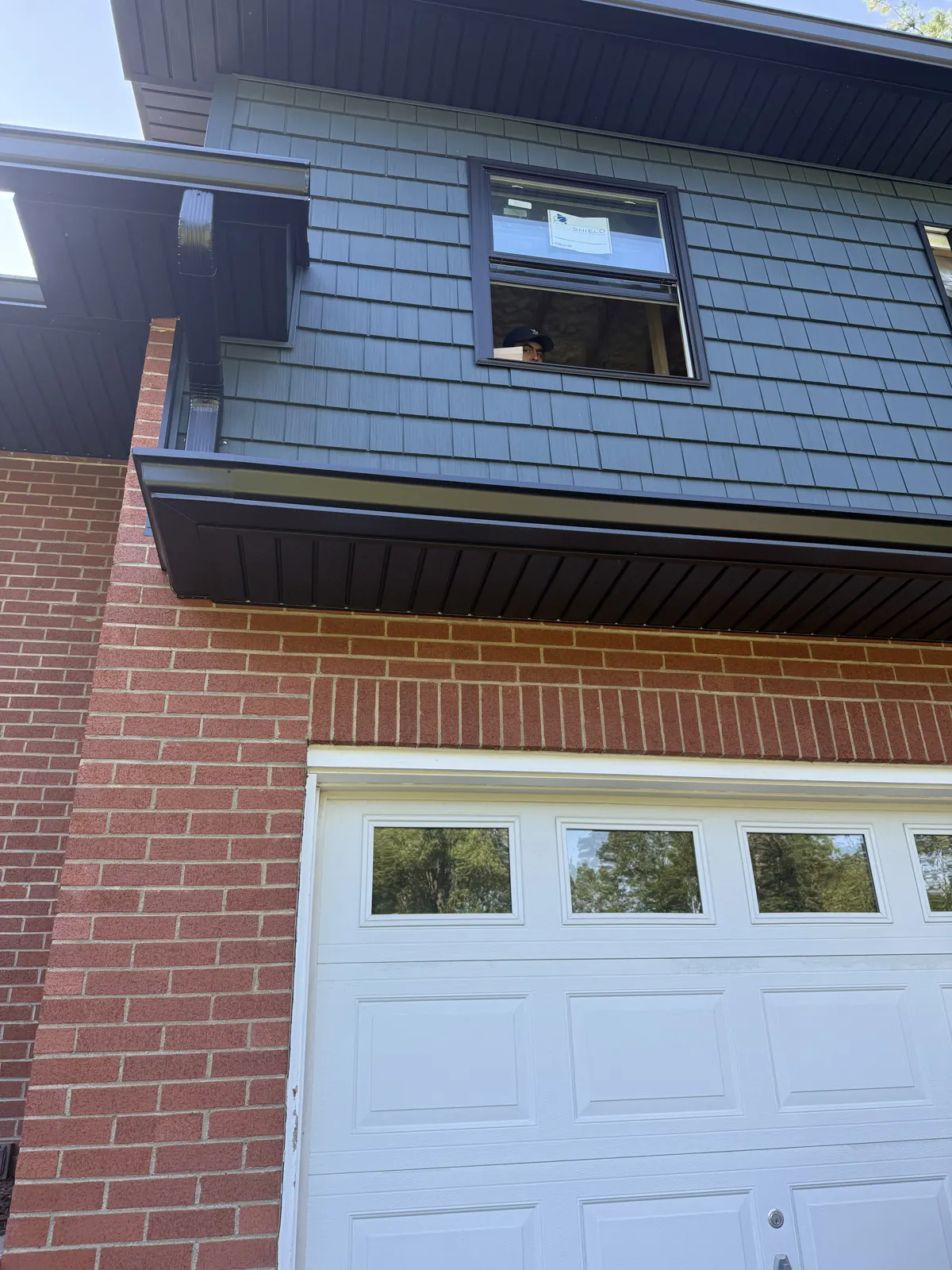 Blue-gray siding above a brick front with a white garage door