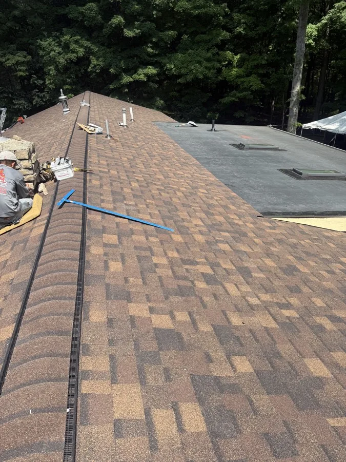 SSKM crew member working on chimney flashing along a shingle roof ridge
