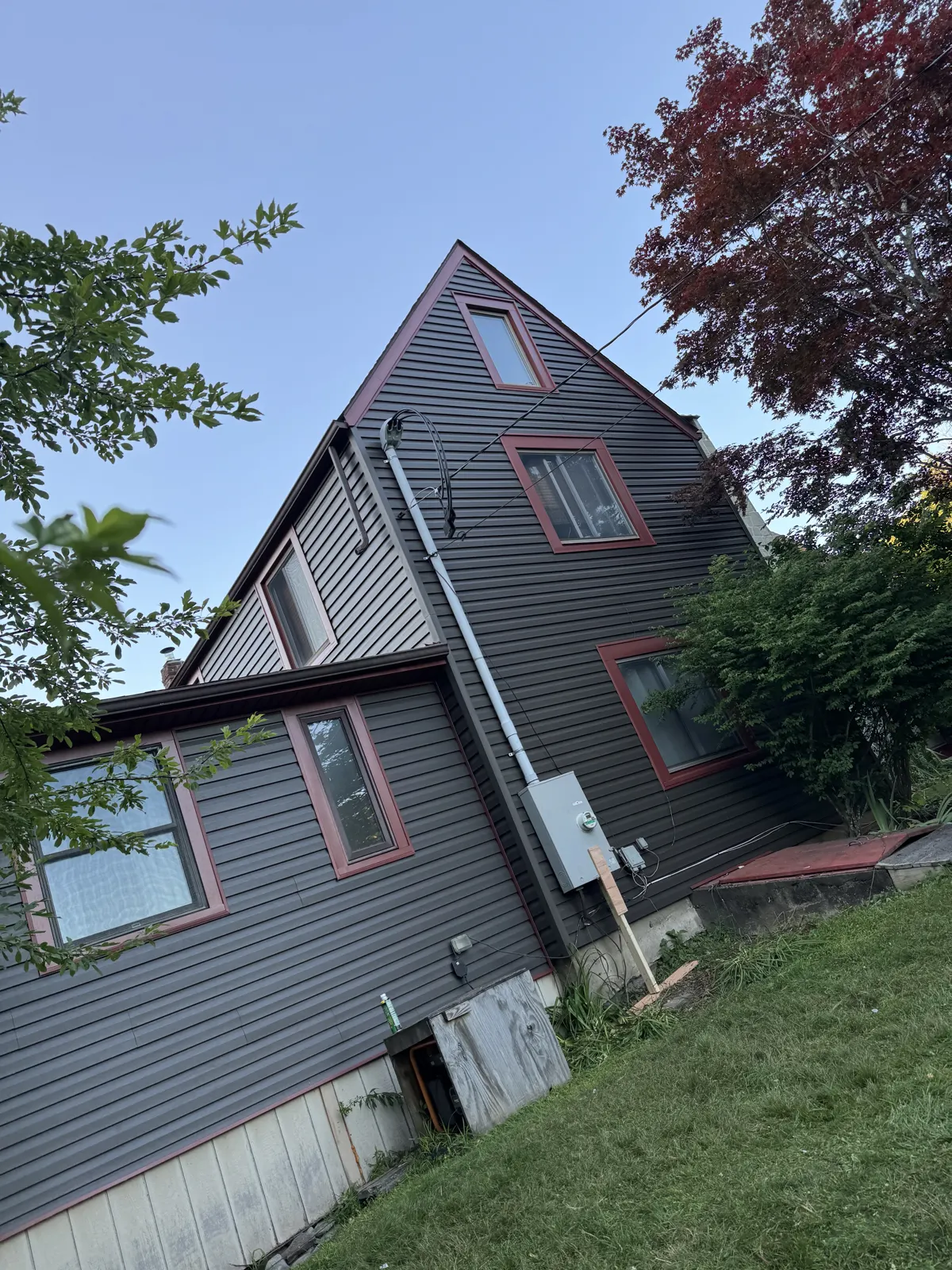 Dark gray siding with red trim on a multi-gable home