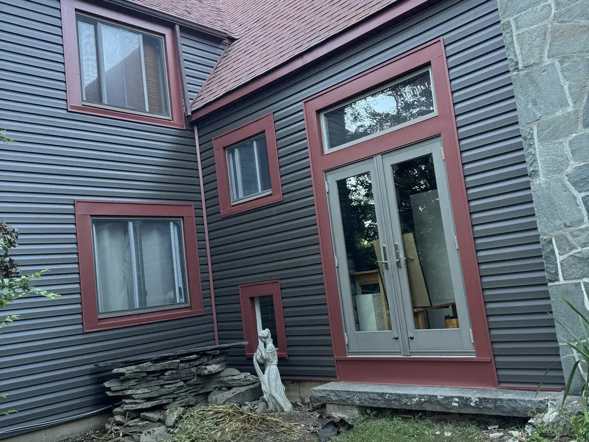 Finished exterior with dark siding and red trim on a home in Lumberland, NY