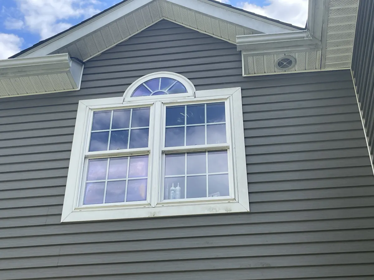 Gray siding and a new arched window on a finished home exterior