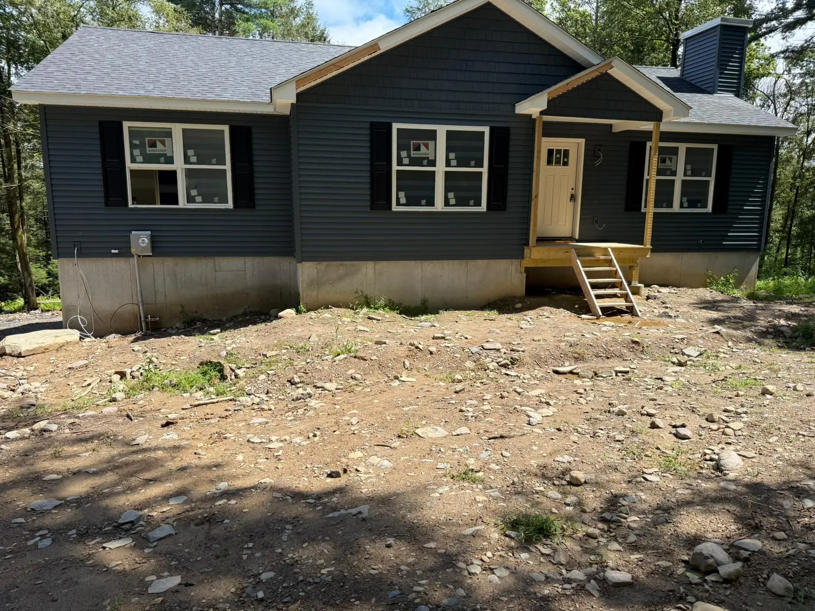 Finished new-construction home with navy siding and a new front entry