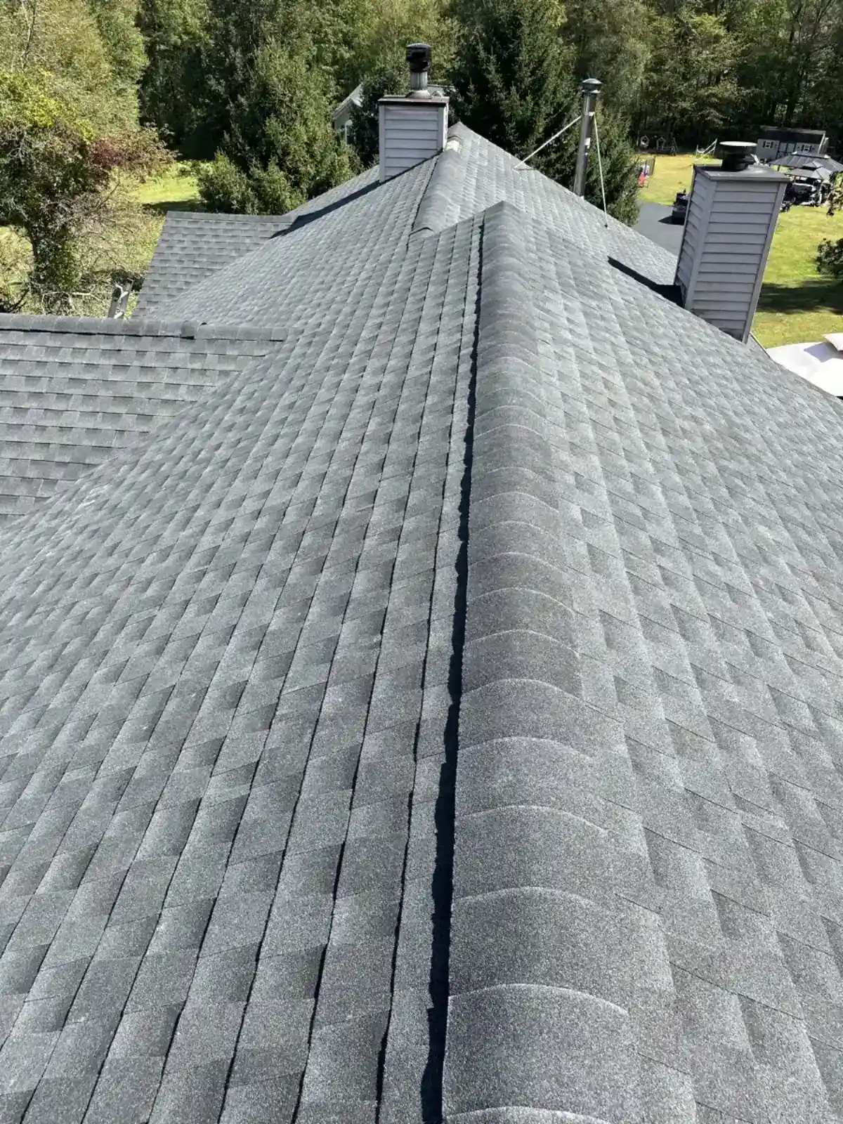 Aerial view of a finished shingle roof ridge with two chimneys
