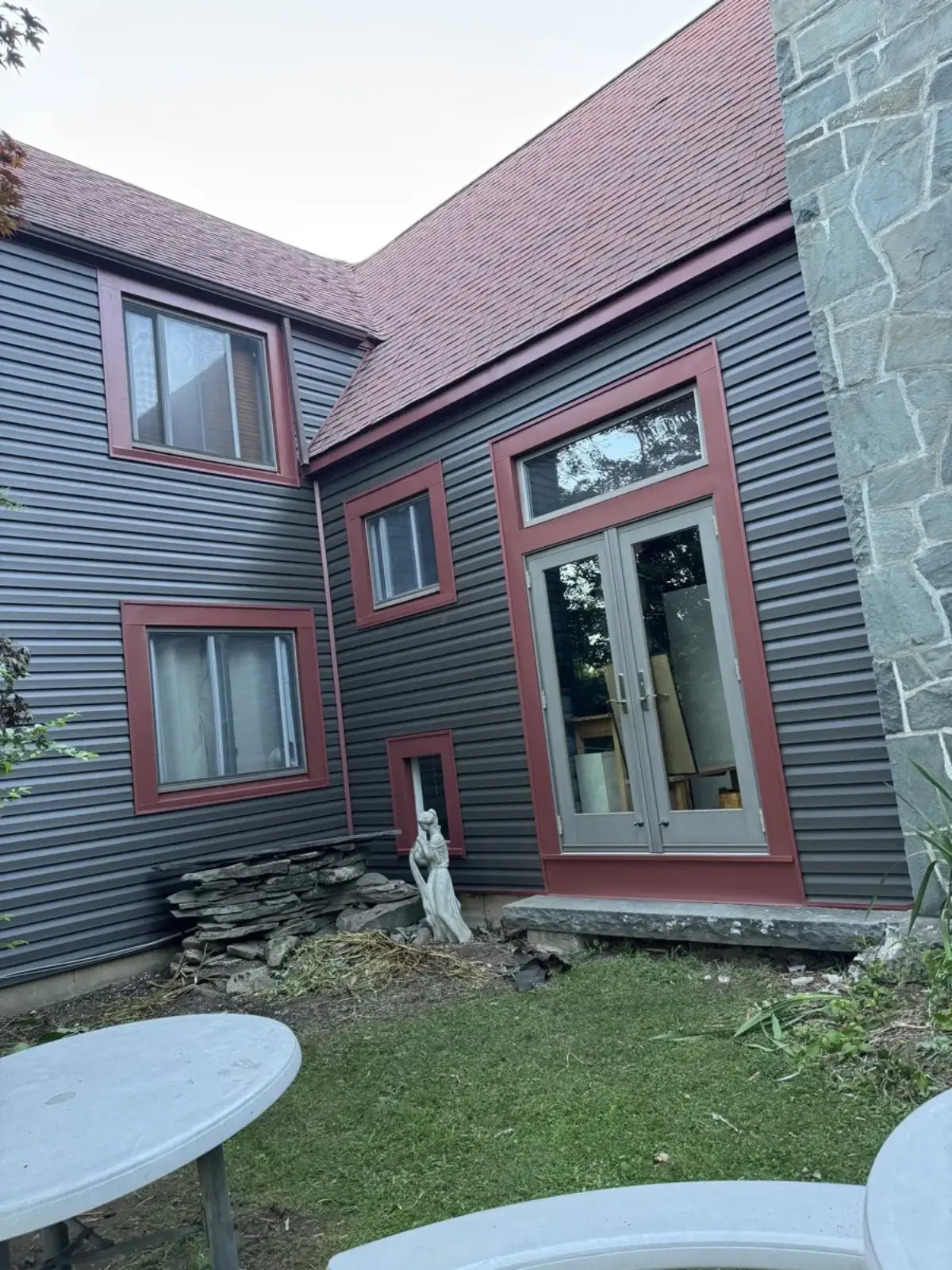 Finished dark siding with red trim and French doors on a home exterior
