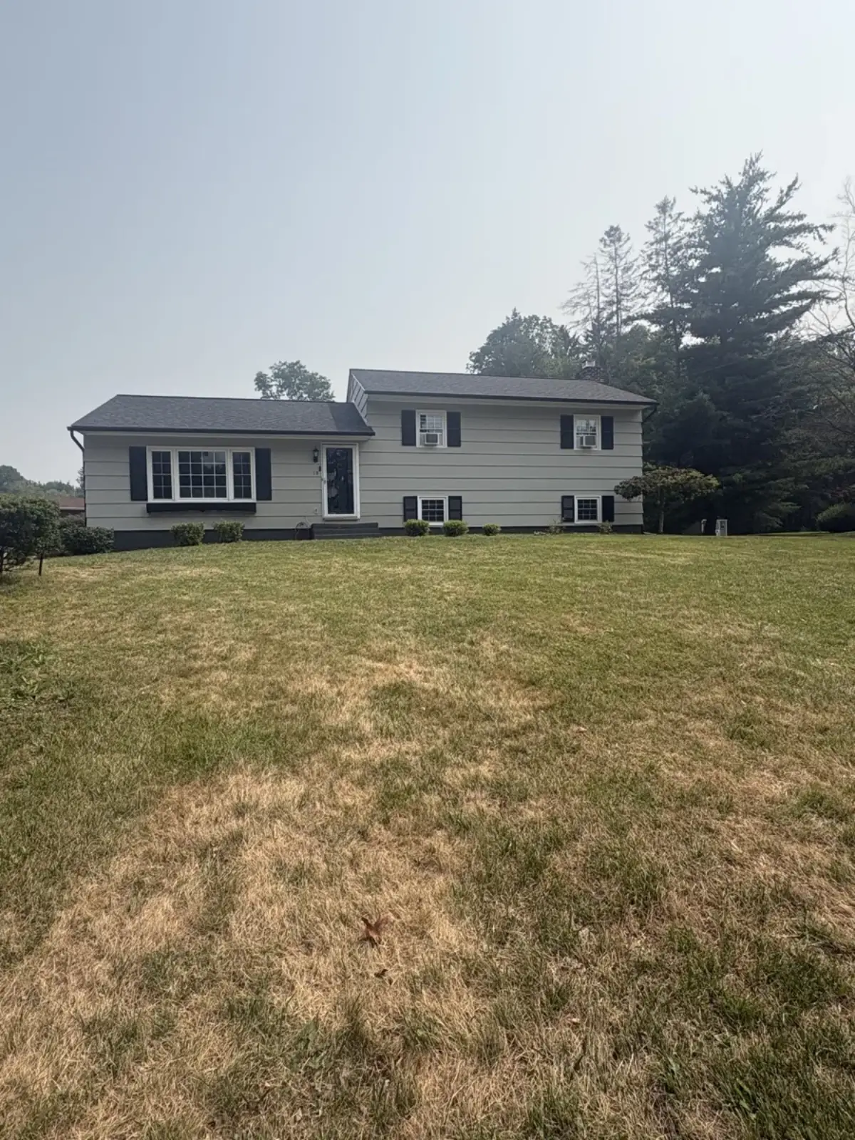 Finished siding on a split-level home with black shutters