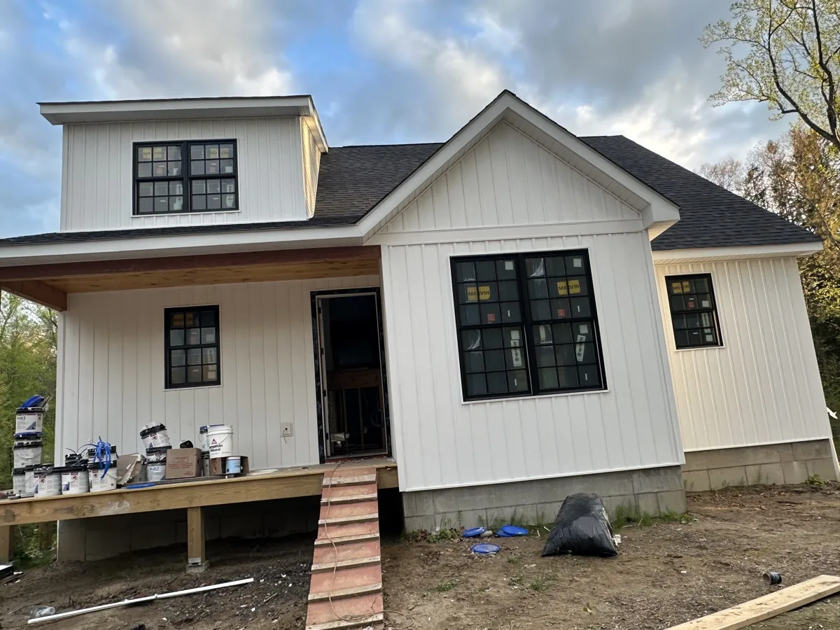 Near-complete new construction home with board-and-batten siding and new windows
