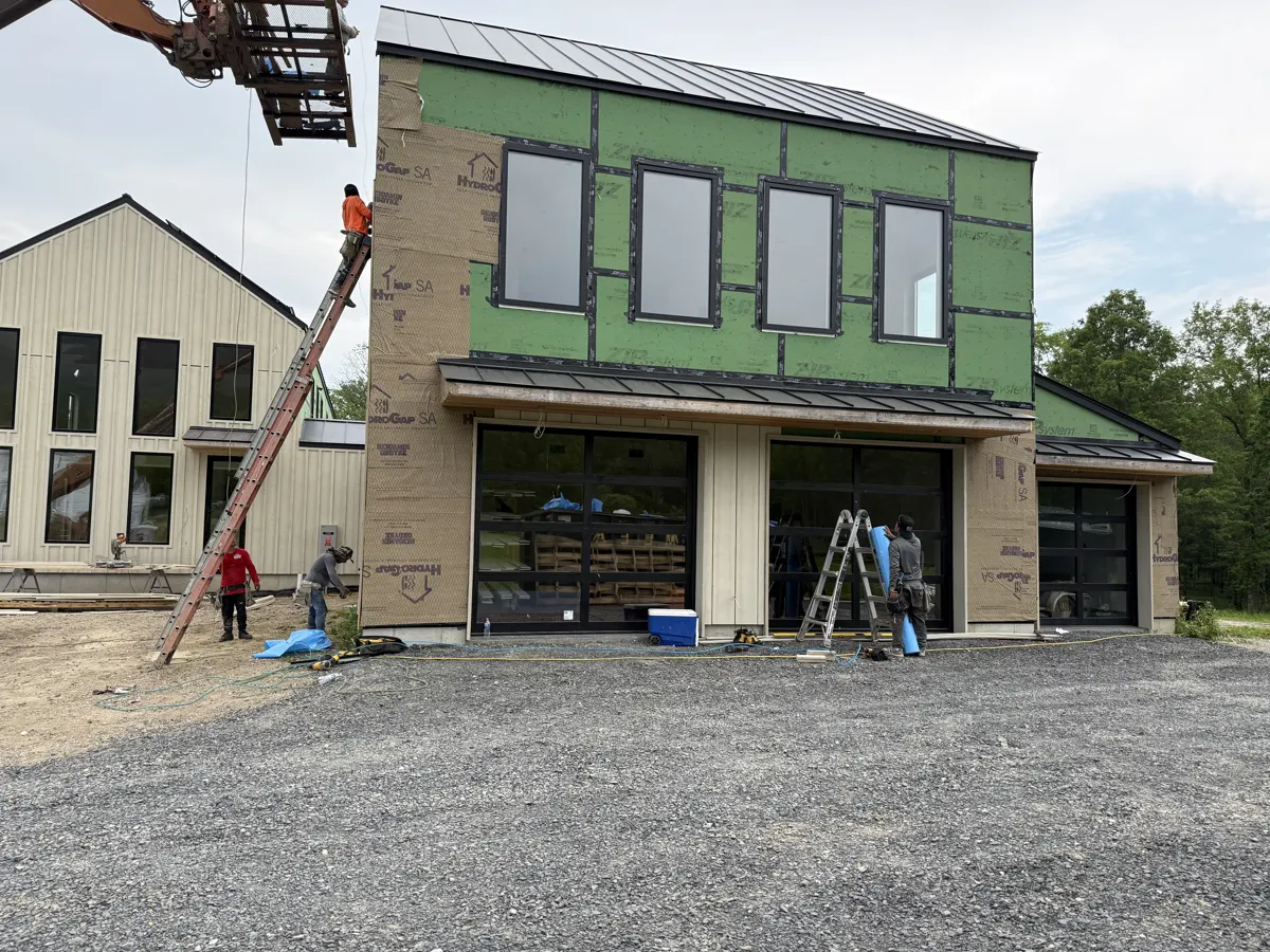 New construction home wrapped in green sheathing with a garage