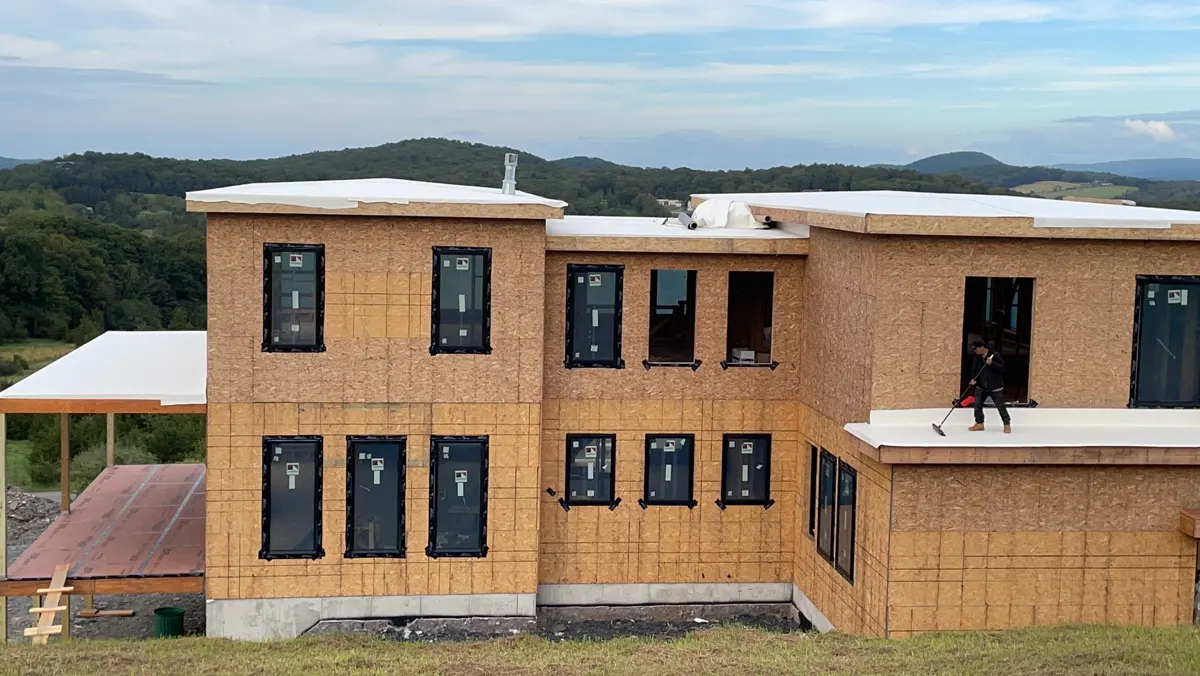 New construction two-story home with sheathing and black windows installed