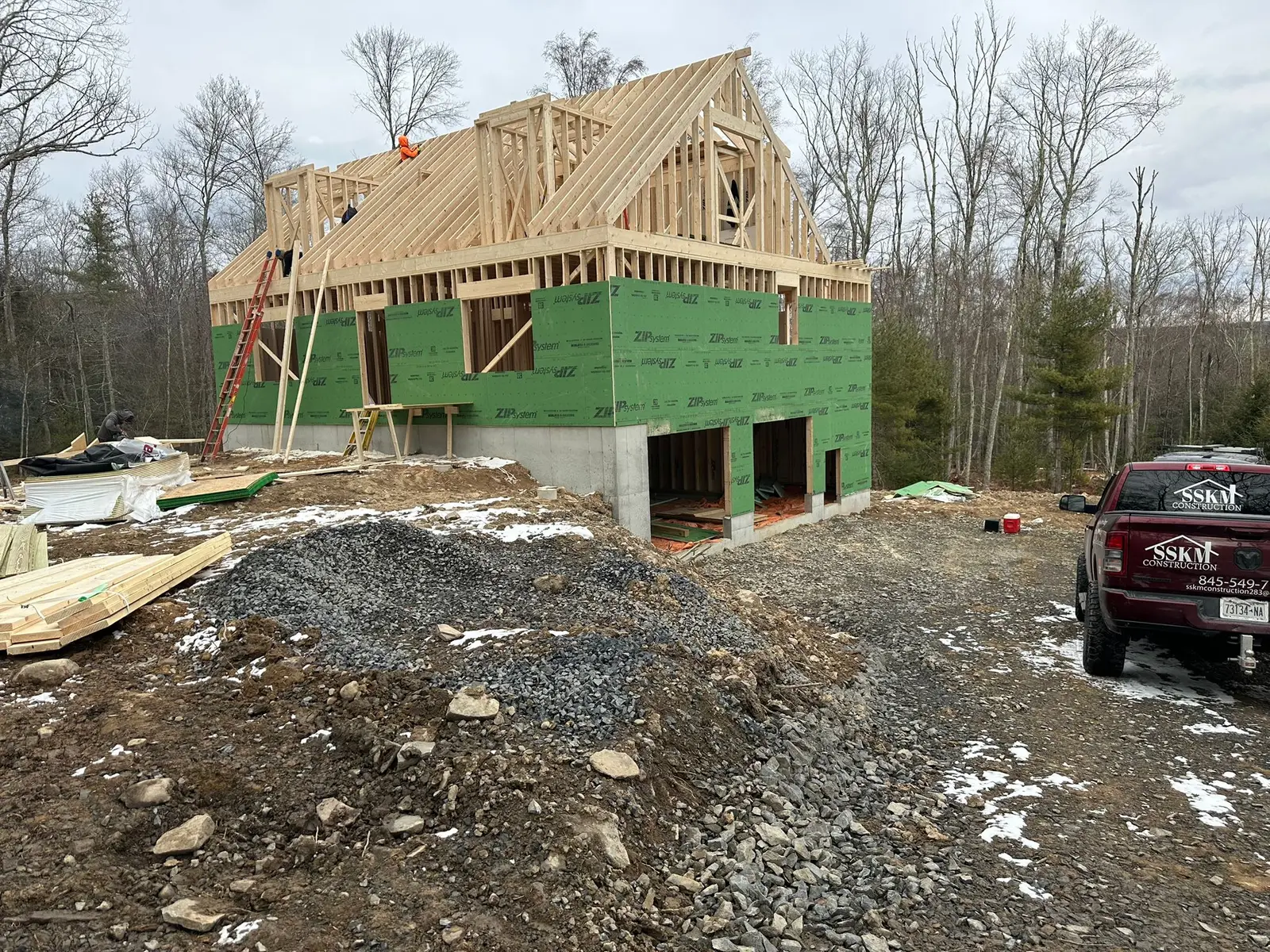 New-construction framing wrapped in ZIP system sheathing, with the SSKM Construction truck on site