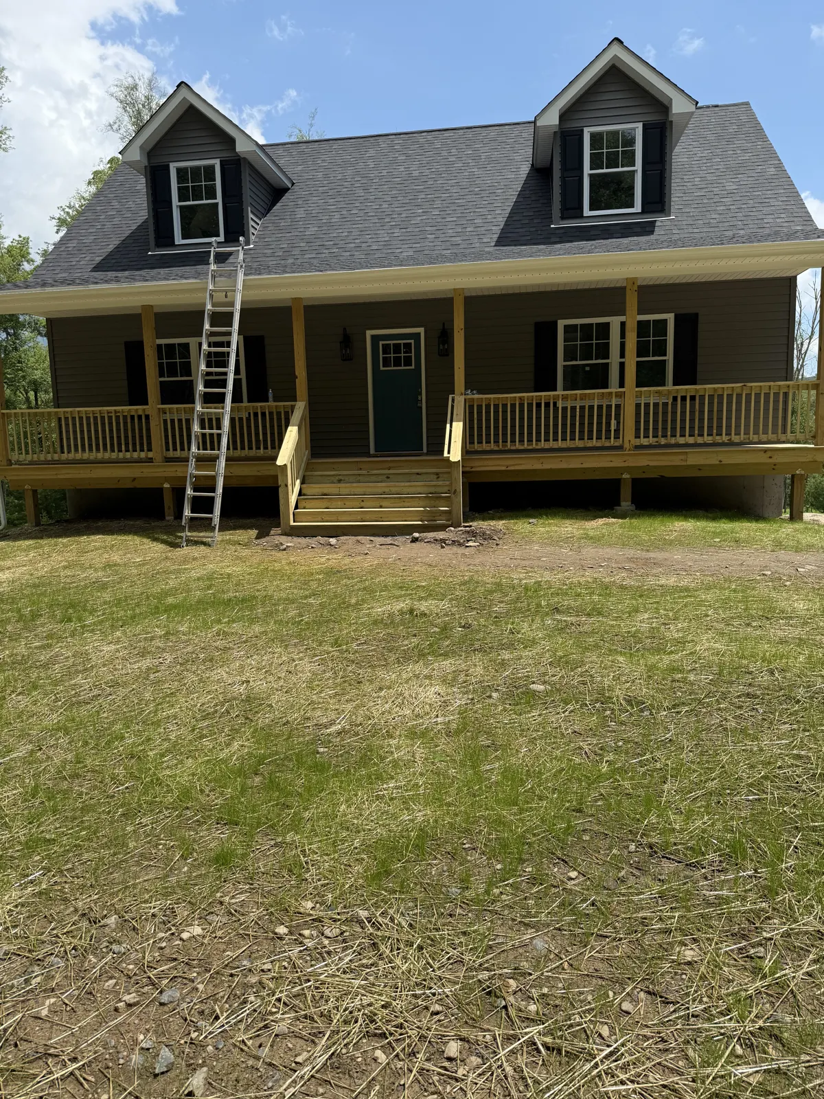 New covered front porch with wood railings and stairs on a new home
