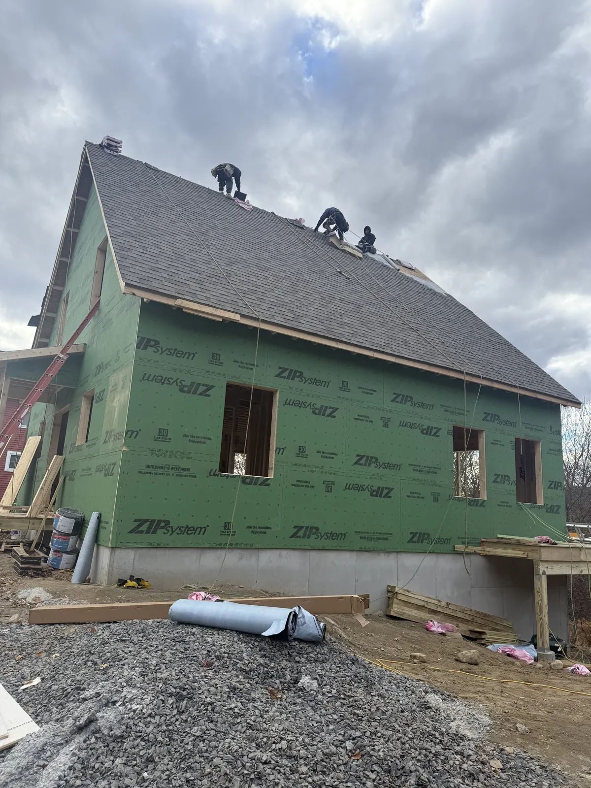 New home wrapped in green sheathing with the roof going on