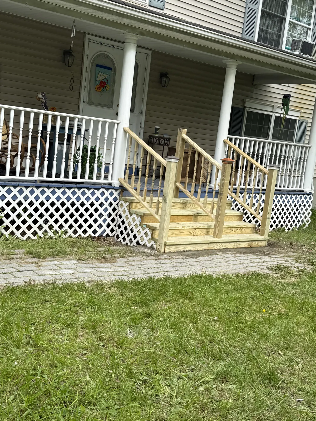 New wood porch steps and railing on a home with white lattice skirting
