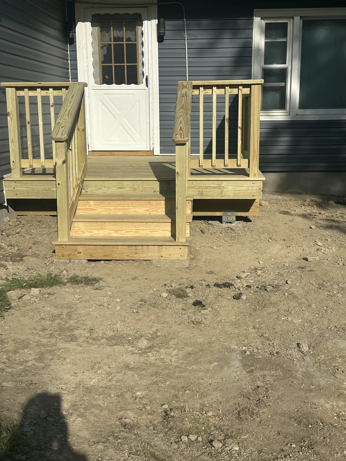 New wood deck with stairs and railing at a gray home
