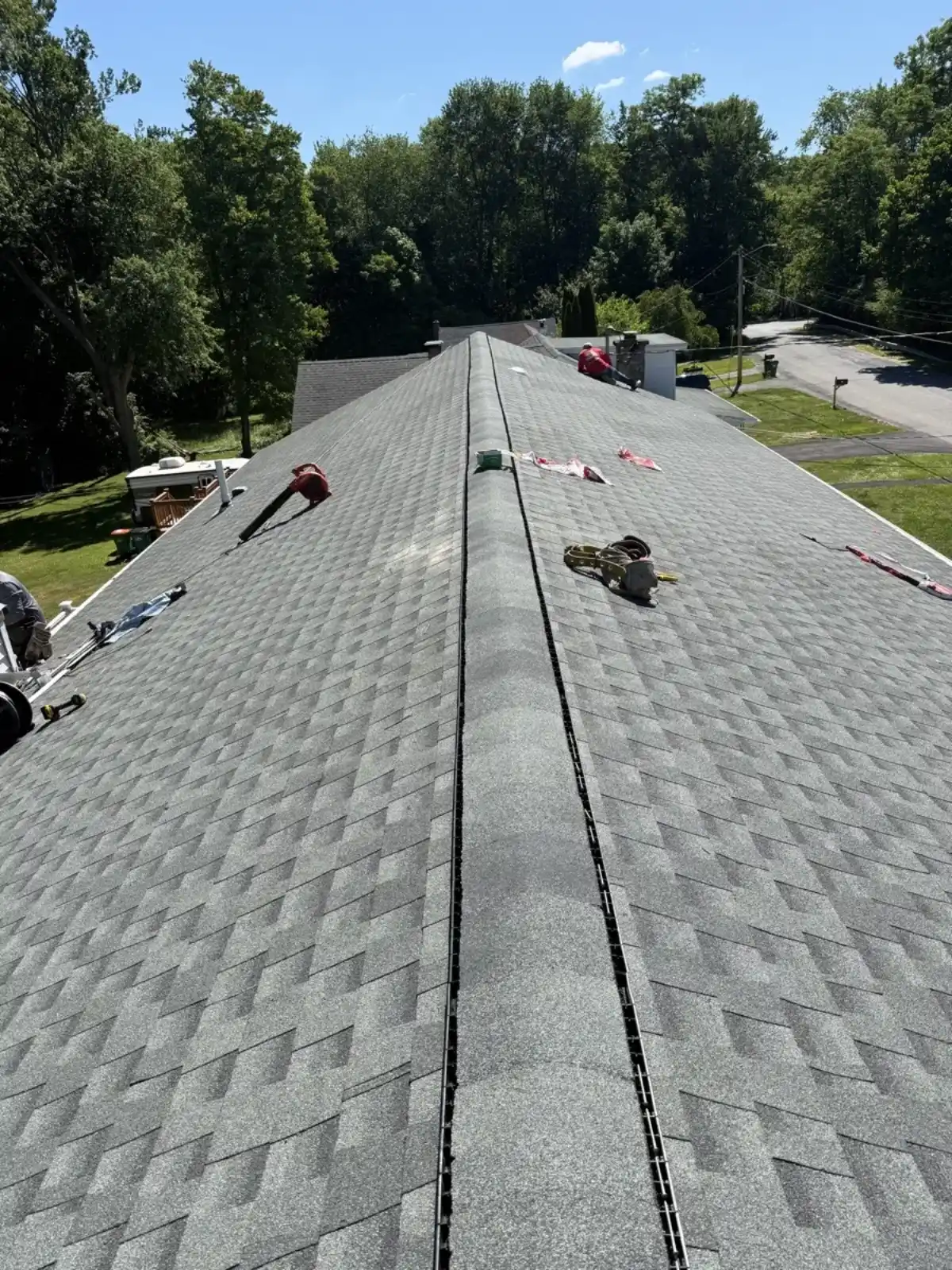 Crew installing ridge cap shingles on a finished roof