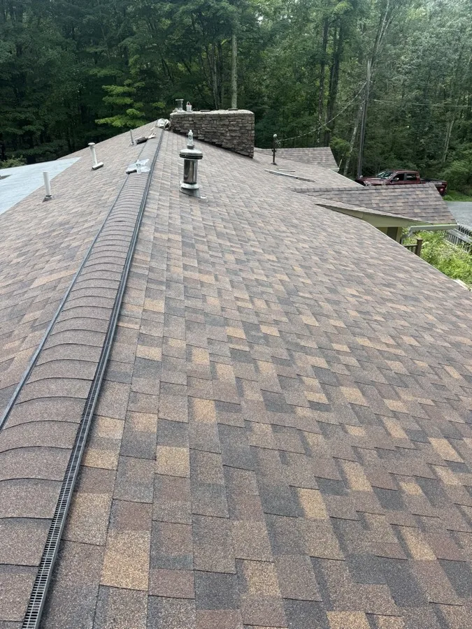 Ridge line and stone chimney flashing on a large shingle roof