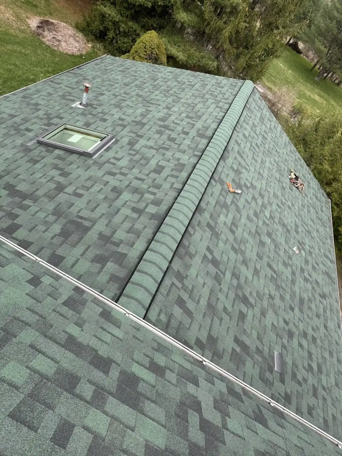 Aerial view of a crew member installing shingles near a skylight