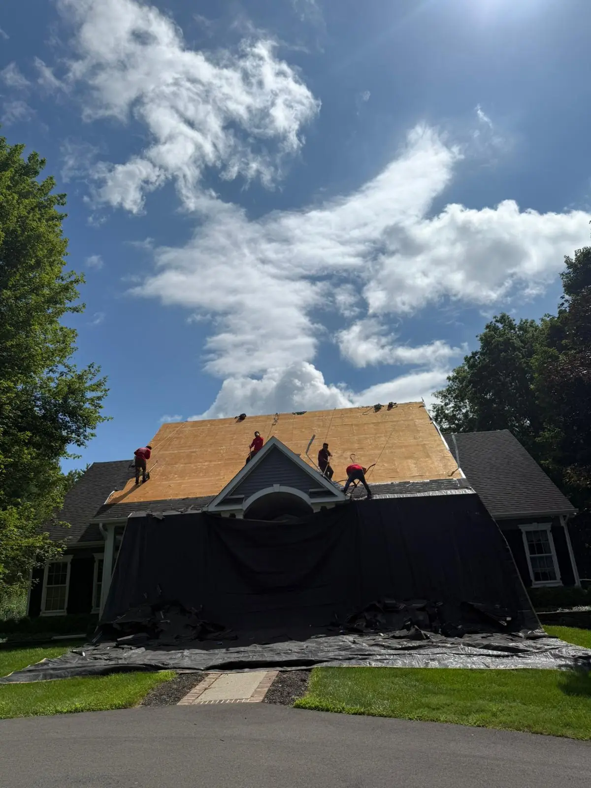 Full roof re-deck in progress, with tarps down to protect the yard and driveway