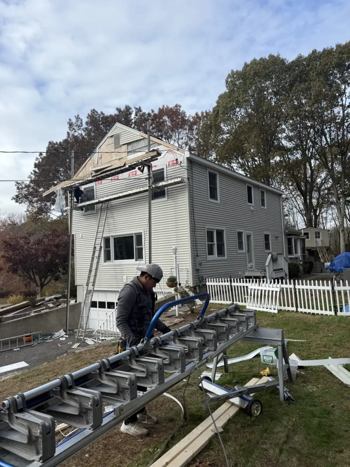 Siding installation in progress on a home addition with scaffold and ladder set up