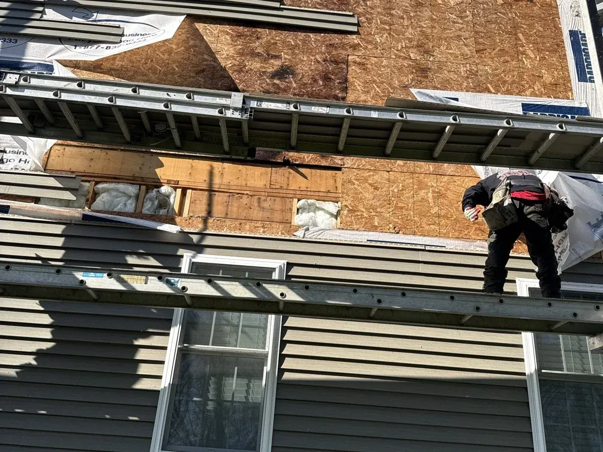 Installers hanging new gray siding on a two-story home