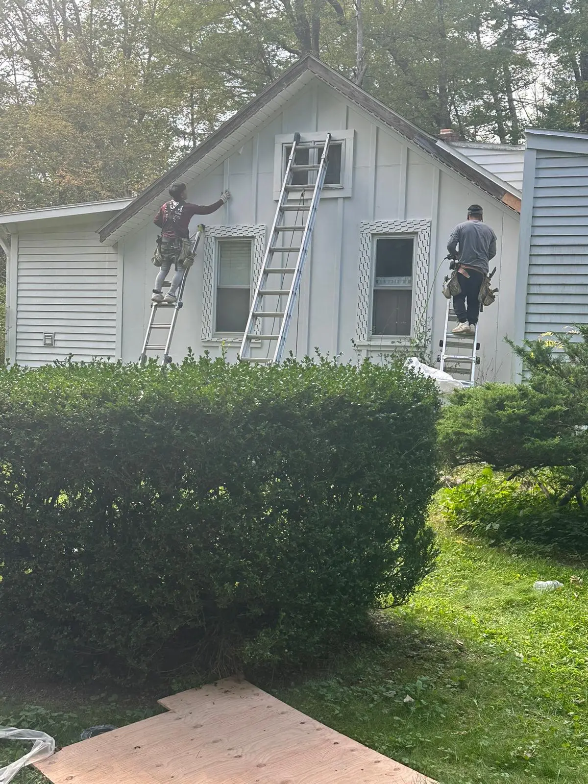 Crew installing board-and-batten siding on a gable end