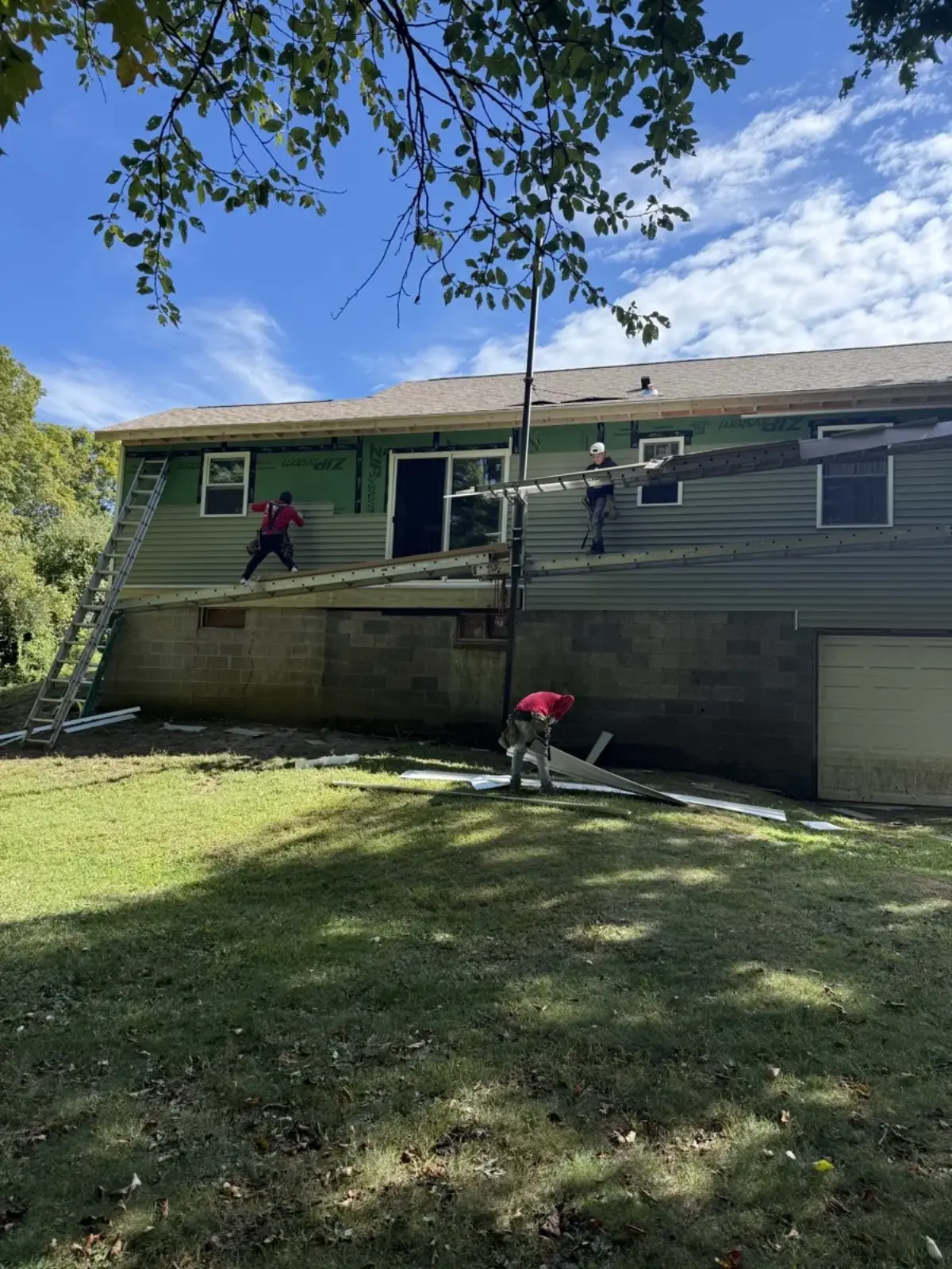 Crew installing new siding from scaffolding over ZIP system sheathing