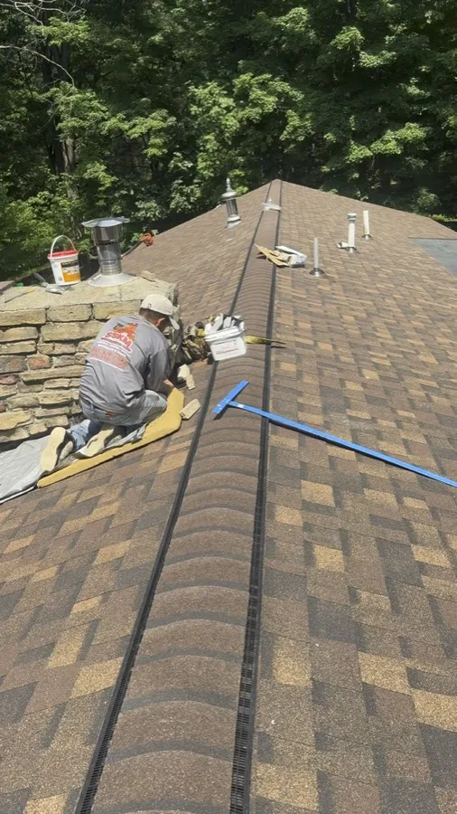 SSKM Construction crew member in company shirt working on stone chimney flashing